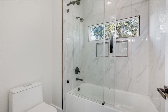 bathroom featuring toilet and combined bath / shower with glass door