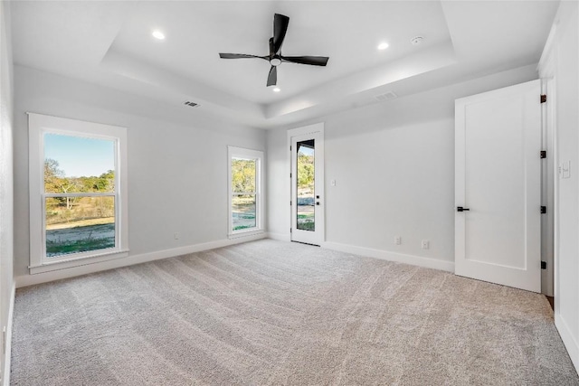 carpeted empty room featuring a raised ceiling and ceiling fan