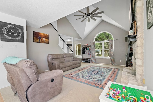 living room with a textured ceiling, light colored carpet, vaulted ceiling, ceiling fan, and a fireplace