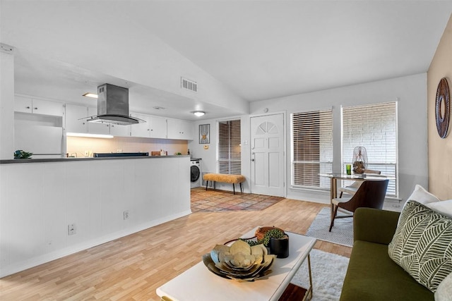 living room with vaulted ceiling, washer / clothes dryer, and light hardwood / wood-style flooring