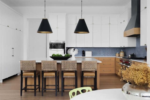 2005 Far Gallant Dr, Austin, TX 78746 - kitchen featuring wall chimney range hood, a kitchen bar, dark wood-type flooring, backsplash, and light countertops