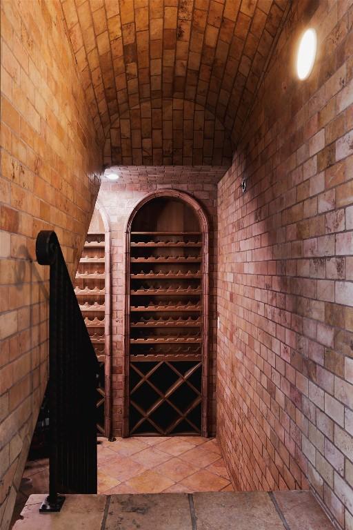 wine room featuring lofted ceiling, brick ceiling, and brick wall