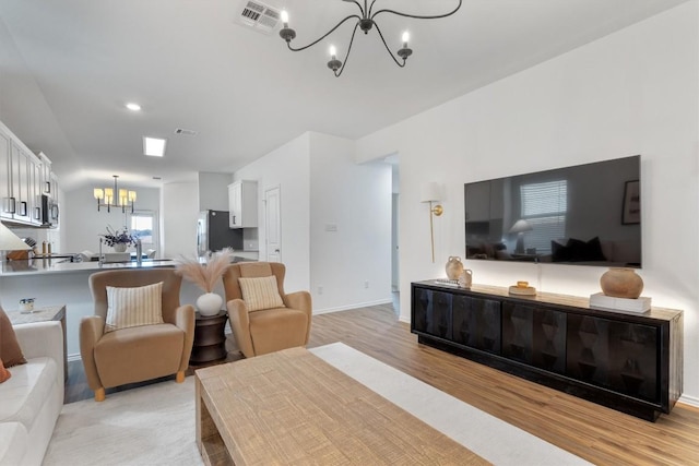 living room featuring light hardwood / wood-style flooring and an inviting chandelier