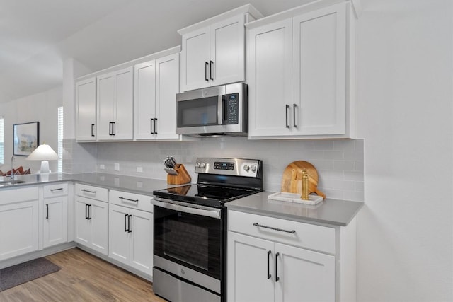 kitchen featuring decorative backsplash, light wood-type flooring, stainless steel appliances, sink, and white cabinets