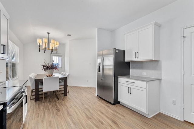 kitchen with backsplash, light wood-type flooring, appliances with stainless steel finishes, a notable chandelier, and white cabinetry