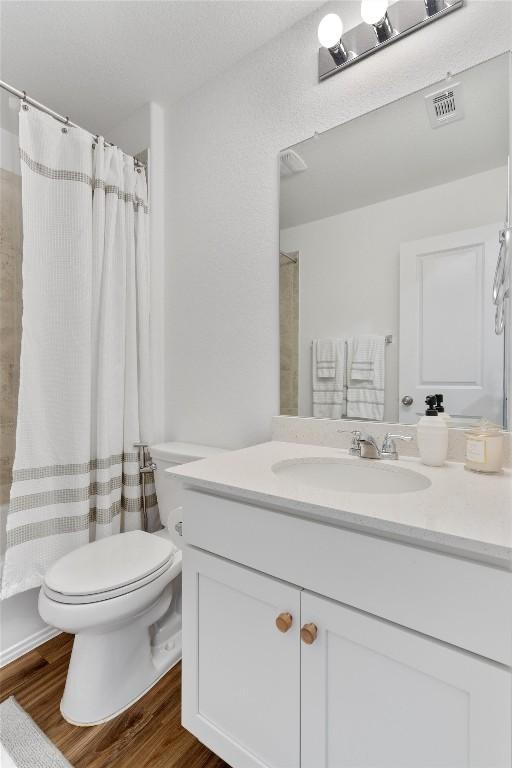 full bathroom featuring shower / bath combo, vanity, hardwood / wood-style flooring, and toilet