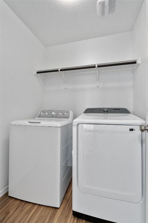 clothes washing area with light wood-type flooring and separate washer and dryer