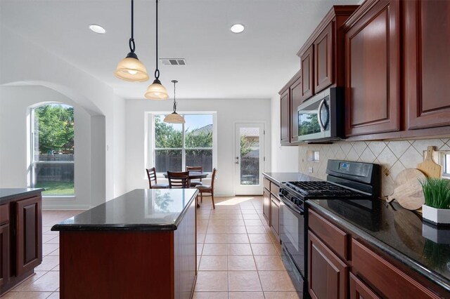 kitchen with light tile patterned floors, black range with gas stovetop, pendant lighting, decorative backsplash, and a kitchen island