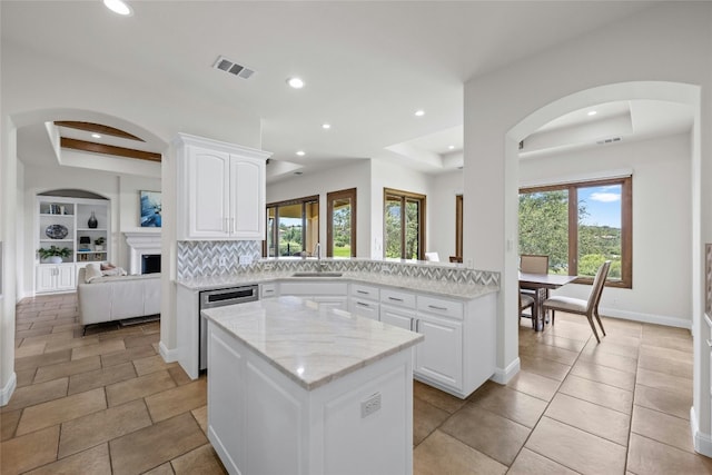 kitchen with visible vents, white cabinets, light stone counters, open floor plan, and a tray ceiling