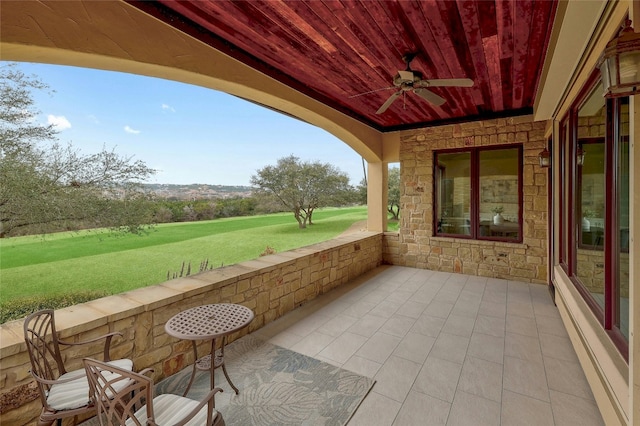 view of patio featuring view of golf course and a ceiling fan