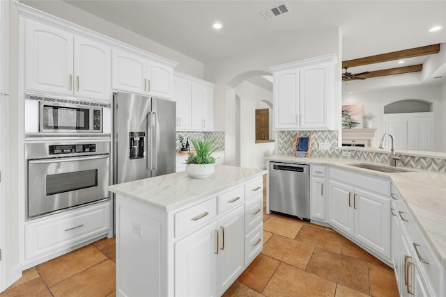 kitchen with arched walkways, white cabinets, visible vents, stainless steel appliances, and a sink