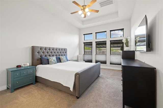 bedroom featuring light carpet, a raised ceiling, and ceiling fan