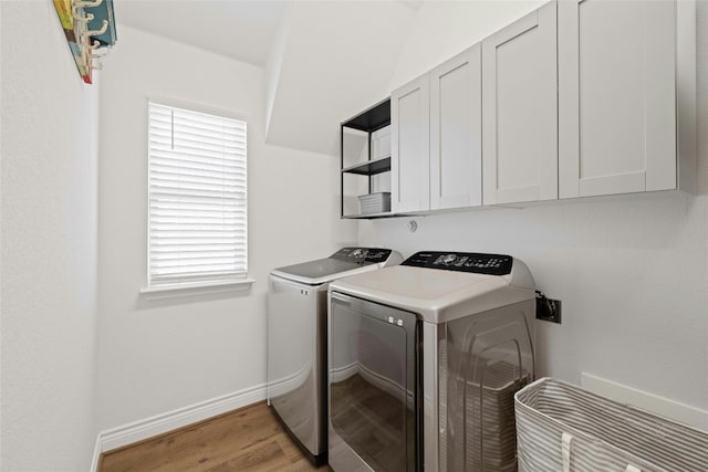 clothes washing area featuring cabinets, washer and dryer, a wealth of natural light, and light wood-type flooring