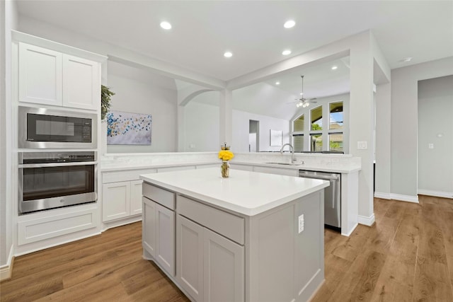 kitchen featuring a kitchen island, sink, white cabinets, kitchen peninsula, and stainless steel appliances