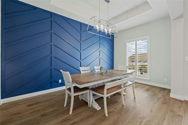 dining space featuring hardwood / wood-style floors, a chandelier, and a tray ceiling