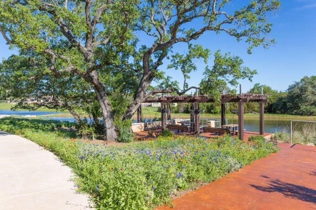 view of community featuring a water view and a pergola