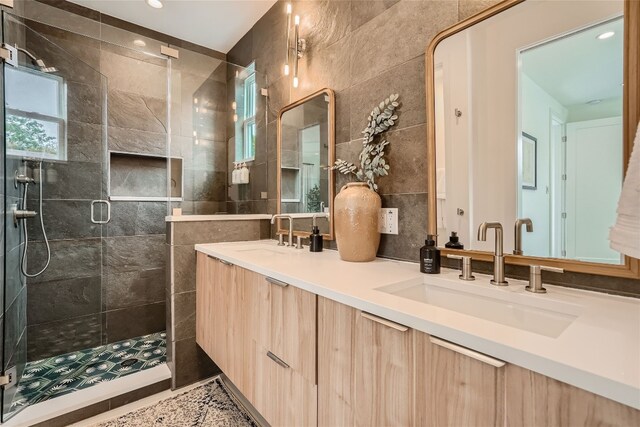 bathroom with vanity, a shower with door, a healthy amount of sunlight, and tile walls