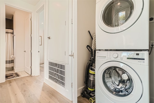 washroom with stacked washer / dryer and light hardwood / wood-style flooring