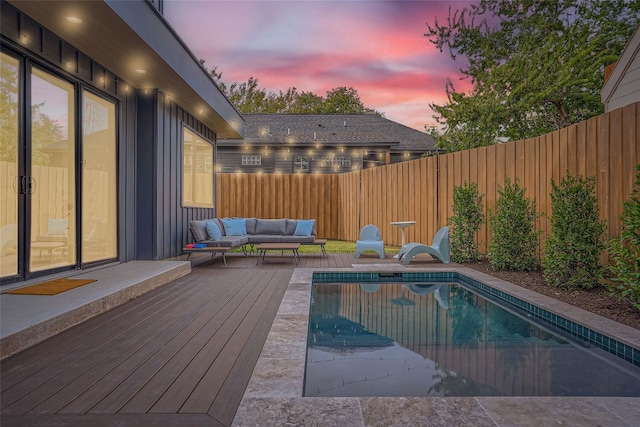 pool at dusk with an outdoor living space and a deck