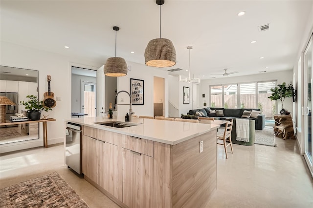 kitchen featuring light brown cabinetry, ceiling fan, sink, decorative light fixtures, and an island with sink