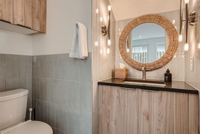 bathroom featuring toilet, tile walls, and sink