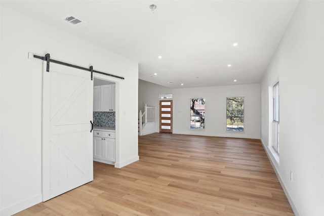 empty room with a barn door and light wood-type flooring