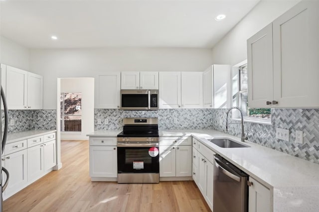 kitchen featuring sink, white cabinets, stainless steel appliances, and light hardwood / wood-style floors