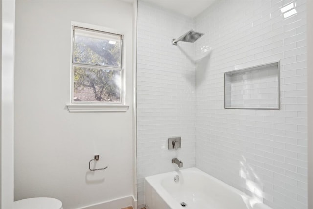 bathroom featuring tiled shower / bath combo and toilet