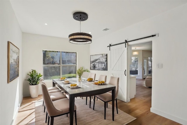 dining area featuring a barn door and light hardwood / wood-style floors