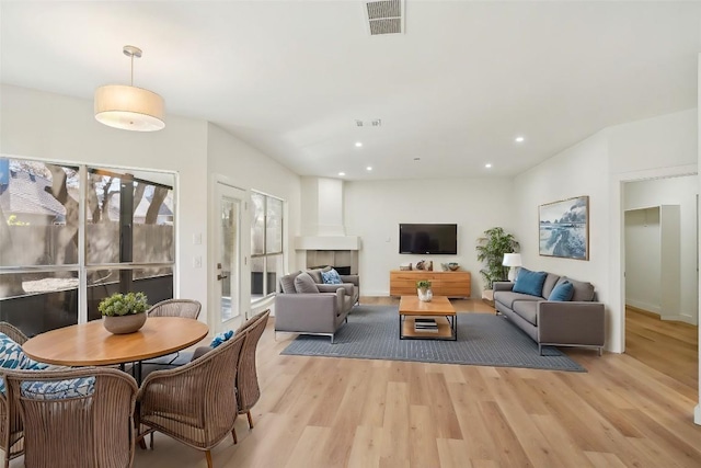 living area with light wood-style floors, recessed lighting, visible vents, and a tile fireplace