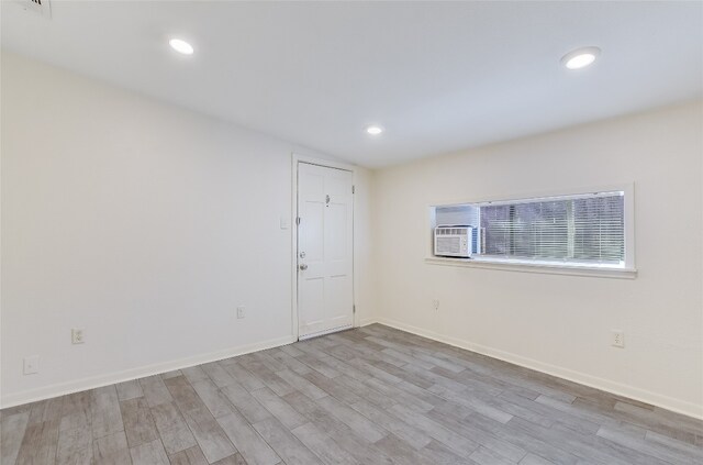 spare room featuring a wall unit AC and light wood-type flooring