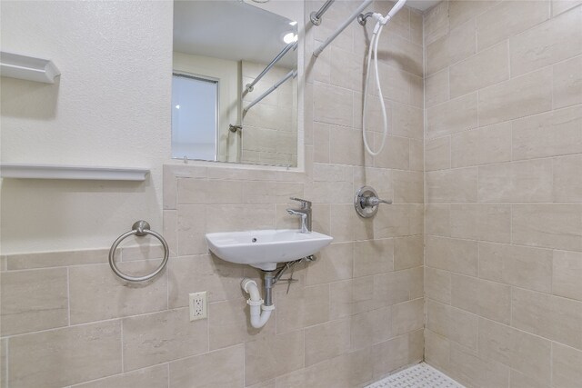 bathroom with a tile shower and sink