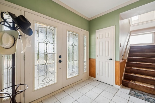 doorway with light tile patterned flooring, french doors, crown molding, and wood walls