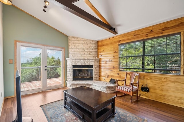 living room with a brick fireplace, wooden walls, lofted ceiling with beams, and wood-type flooring