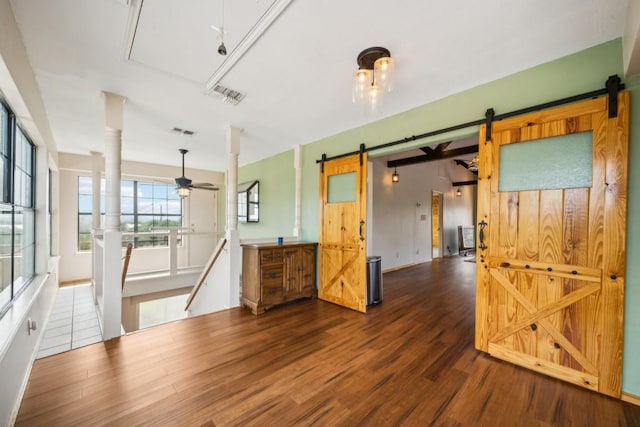 spare room with a barn door, ceiling fan, and dark hardwood / wood-style floors