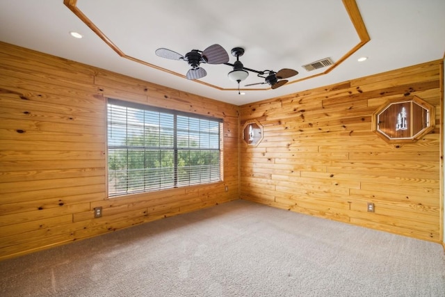 carpeted empty room with wood walls and ceiling fan