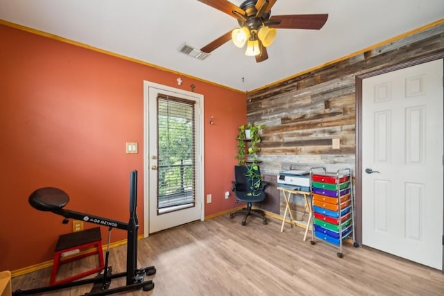 office space featuring ceiling fan, light wood-type flooring, and wooden walls