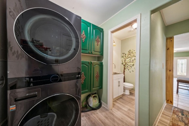 washroom featuring cabinets, light wood-type flooring, stacked washer and dryer, and sink