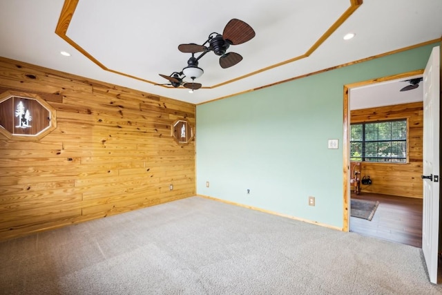 carpeted spare room with ceiling fan, ornamental molding, and wooden walls