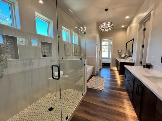 bathroom with a shower with door, vanity, wood-type flooring, and an inviting chandelier