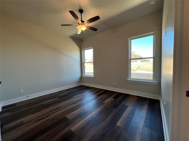 spare room with a healthy amount of sunlight, ceiling fan, and dark wood-type flooring