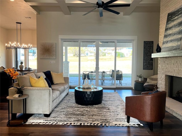 living room featuring beam ceiling, coffered ceiling, hardwood / wood-style floors, a fireplace, and ceiling fan with notable chandelier