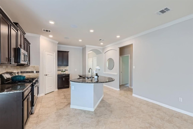 kitchen with sink, dark stone countertops, a kitchen island with sink, and appliances with stainless steel finishes