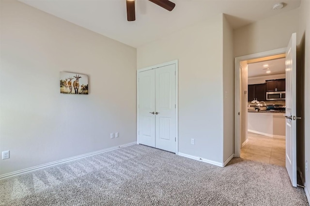 unfurnished bedroom with carpet flooring, ceiling fan, and a closet