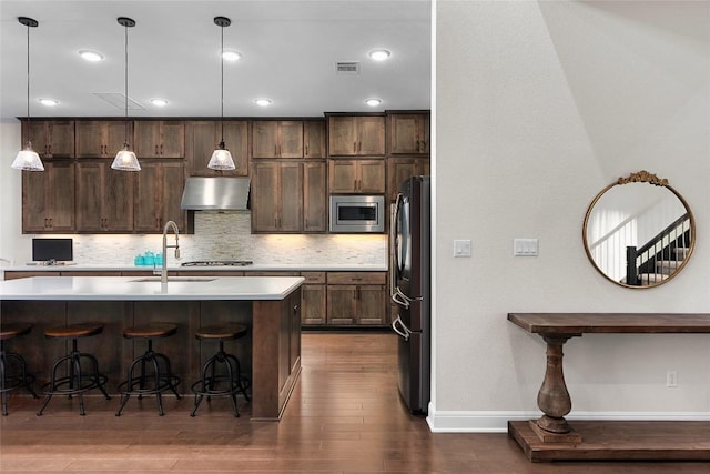 kitchen with backsplash, stainless steel appliances, sink, exhaust hood, and hanging light fixtures