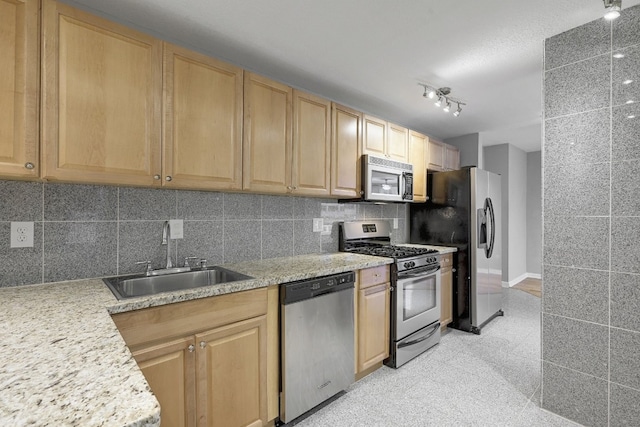 kitchen with tasteful backsplash, sink, stainless steel appliances, light stone countertops, and light brown cabinets