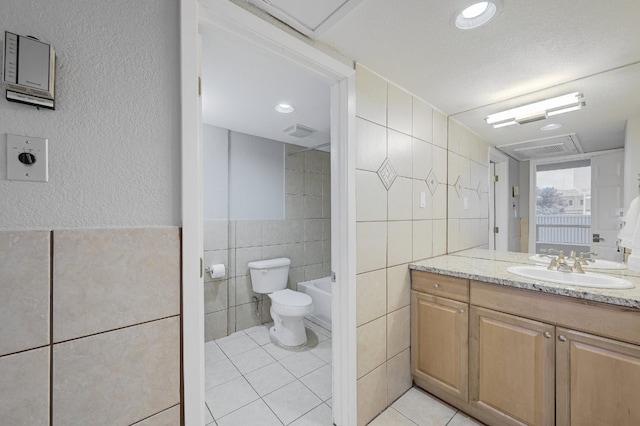 bathroom featuring tile walls, vanity, a washtub, toilet, and tile patterned floors