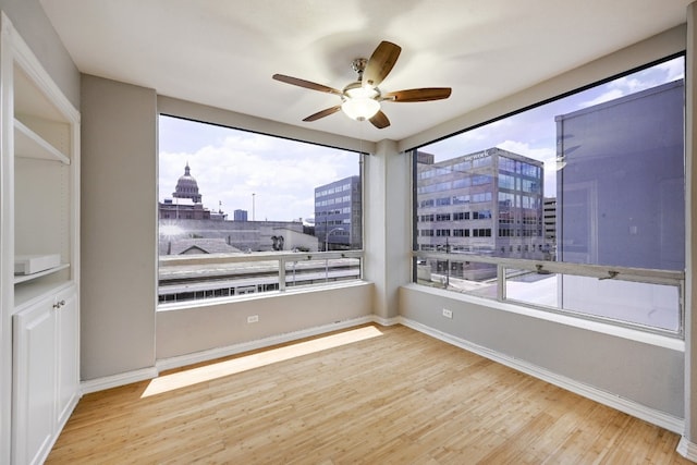 empty room with ceiling fan, a healthy amount of sunlight, and light hardwood / wood-style floors