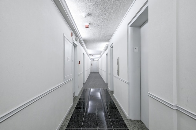 hall with elevator and a textured ceiling