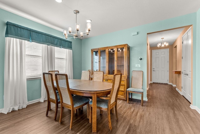 dining area with hardwood / wood-style flooring and an inviting chandelier